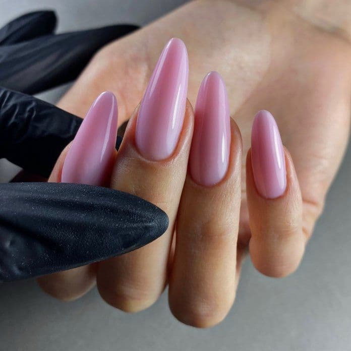 Długie przedłużone na formie paznokcie w odcieniu różu w kształcie migdał uzyskane po kursie Gel System